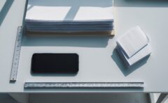 Aufsicht von oben auf einen aufgeräumten weißen Schreibtisch mit Smartphone und Papier als Symbolbild für Web-Messdaten