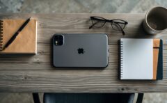 Aufsicht von oben auf einen Schreibtisch mit Smartphone, Notizbuch und Kaffeetasse in kühlem Tageslicht