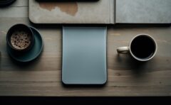 Smartphone und Notizbuch auf einem Schreibtisch von oben fotografiert, symbolisch fuer Einschraenkungen bei einer kostenlosen KI-App