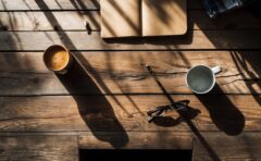 Blick von oben auf einen Holzschreibtisch mit Bleistift, Tasse und Lesebrille - Symbolbild zum Clixplora Morning Briefing vom 09.10.2026
